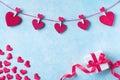 Valentines day background. Garland of red hearts on clothespins and gift box