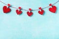 Valentines day background. Garland of red hearts on clothespins on turquoise wall