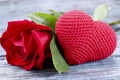 Valentines day background. On a gray wooden background in the center is a red knitted heart and a red rose. Royalty Free Stock Photo