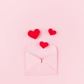 Valentines day background of pink paper envelop and stream soar red small hearts on pink paper background.