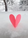Valentines Day background. Pink paper heart on fluffy snowy background.