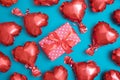 Valentines Day background. Red heart shape balloons and gift box on turquoise background flat lay, top view