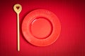 Valentines Day background with red plate and wooden spoon with heart on red background Royalty Free Stock Photo