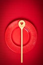 Valentines Day background with red plate and wooden spoon with heart on red background Royalty Free Stock Photo
