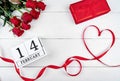 Valentines Day background with red ribbon shaped as heart, bouquet of roses, gift box and february 14 on wood table. Love Royalty Free Stock Photo