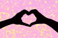 Valentines day background, silhouette of two hands making a heart shape together a pink and sparkly background with Royalty Free Stock Photo