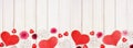 Valentines Day banner with border of hearts, flowers and decor against a white wood background with copy space