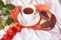 Valentines Day breakfast in the bed - heart shaped cookies and coffee cup on the sheets among red roses. Aesthetics Royalty Free Stock Photo