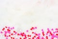 Valentines Day candy heart sprinkles bottom border over a white textured background Royalty Free Stock Photo