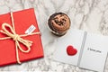 Valentines day card background with red present gift box on marble table next to chocolate cupcake love heart shape cookie and Royalty Free Stock Photo