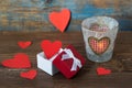 Valentines day card, red hearts in a gift box and burning candle with hearts on wooden background Royalty Free Stock Photo