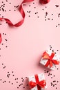 Valentines day card template with gifts, red ribbon, confetti on pink background. Flat lay, top view, copy space Royalty Free Stock Photo