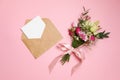 Valentines day composition: bouquet of flowers, kraft envelope with greeting card lay at pink background. Woman`s day card templa