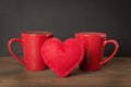 Valentines day composition with red coffee cups and felt heart over wooden board with chalckboard as background. Copy space. Royalty Free Stock Photo