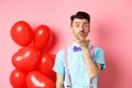 Valentines day concept. Attractive and funny man in bow-tie, blowing air kiss to lover, standing near pink background