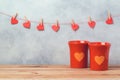 Valentines day concept with coffee cups and heart shapes over background with garland