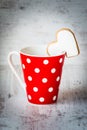 Valentines day concept. Coffee red polka dotted cup with a heart shaped homemade cookie over white wood background. Royalty Free Stock Photo