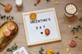 Valentines day concept flat lay with flowers, sweets and a board with text on the wooden background. Royalty Free Stock Photo