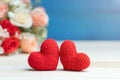 Valentines day concept. hand make two yarn red heart in front of rose flower bouquet on wooden table and blue background Royalty Free Stock Photo