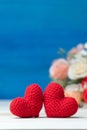 Valentines day concept. hand make two yarn red heart in front of rose flower bouquet on wooden table and blue background Royalty Free Stock Photo