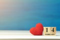 Valentines day concept. hand make yarn red heart beside wooden block calendar set on Valentines date 14 February on wooden table a Royalty Free Stock Photo