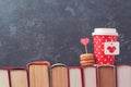 Valentines day concept with paper coffee cup, macarons and vintage books over blackboard Royalty Free Stock Photo