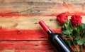 Valentines day. Red wine bottle and red roses on wooden background