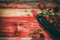 Valentines day. Red wine bottle, rose and a gift on wooden background Royalty Free Stock Photo