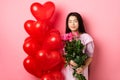 Valentines day concept. Romantic teen asian girl dreaming of love or date, close eyes and smile, holding flowers from Royalty Free Stock Photo