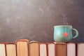 Valentines day concept with tea cup on books over blackboard Royalty Free Stock Photo