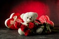 Adorable light brown and white teddy bear with a bouquet of red rose and hearth shaped gift box. Valentines day concept Royalty Free Stock Photo