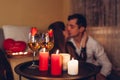 Valentines Day couple kissing at home. Close up of festive drinks wine with strawberries by burning red candles