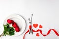 Valentines day dinner with festive table setting, red roses, tape, hearts, ceramic plate, vintage silverware on white Royalty Free Stock Photo