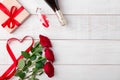 Valentines day dinner romantic setting, red tape, kraft gift box, heart in wine glass, champagne bottle, roses, on white Royalty Free Stock Photo