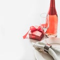 Valentines day dinner with table place setting with red gift, a bottle of champagne on white. Close up. Valentine`s card Royalty Free Stock Photo