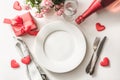 Valentines day dinner with table place setting with red gift, glass for champagne, a bottle of champagne, pink roses, heart orname Royalty Free Stock Photo