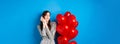 Valentines day. Dreamy romantic woman close eyes and imaging lovely date, standing near heart balloons and smiling, blue