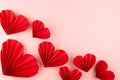 Valentines day festive background in asian style - red paper hearts of folded fans as border soar on gentle pastel pink color.