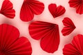 Valentines day festive background in asian style - red paper hearts of folded fans soar on gentle pastel pink color backdrop.
