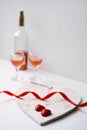 Valentines Day Festive table setting with two glasses of rose wine, red heart shape chocolate candies and red ribbons on Royalty Free Stock Photo