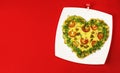 Valentines Day food. Heart shaped pizza with greens, on a white plate, on a red background. Clothespin love. Top view. Royalty Free Stock Photo