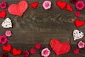 Valentines Day frame of wooden hearts and paper flowers against dark wood