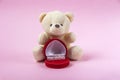 Valentines day gift. Stuffed bear and heart-shaped jewelry box with gold diamond ring on pink background. Marriage proposal Royalty Free Stock Photo