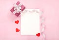 Valentines day greeting card with pink gift box white bow long curved ribbon and paper red hearts Royalty Free Stock Photo