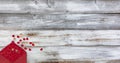 Valentines day greeting concept with envelope of small gold and red hearts pouring out onto a white rustic wood setting