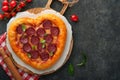 Valentines day heart shaped pizza with mozzarella, pepperoni and basil, wine bottle, two wineglass, gift box on black background. Royalty Free Stock Photo