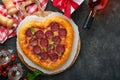 Valentines day heart shaped pizza with mozzarella, pepperoni and basil, wine bottle, two wineglass, gift box on black background. Royalty Free Stock Photo