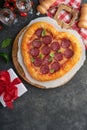 Valentines day heart shaped pizza with mozzarella, pepperoni and basil, wine bottle, two wineglass, gift box on black background. Royalty Free Stock Photo