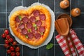 Valentines day heart shaped pizza with mozzarella, pepperoni and basil, wine bottle, two wineglass, gift box on black background. Royalty Free Stock Photo