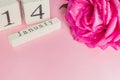 Valentines day and holidays concept - close up of wooden calendar with 14th february date,  and pink rose with water drops  on Royalty Free Stock Photo